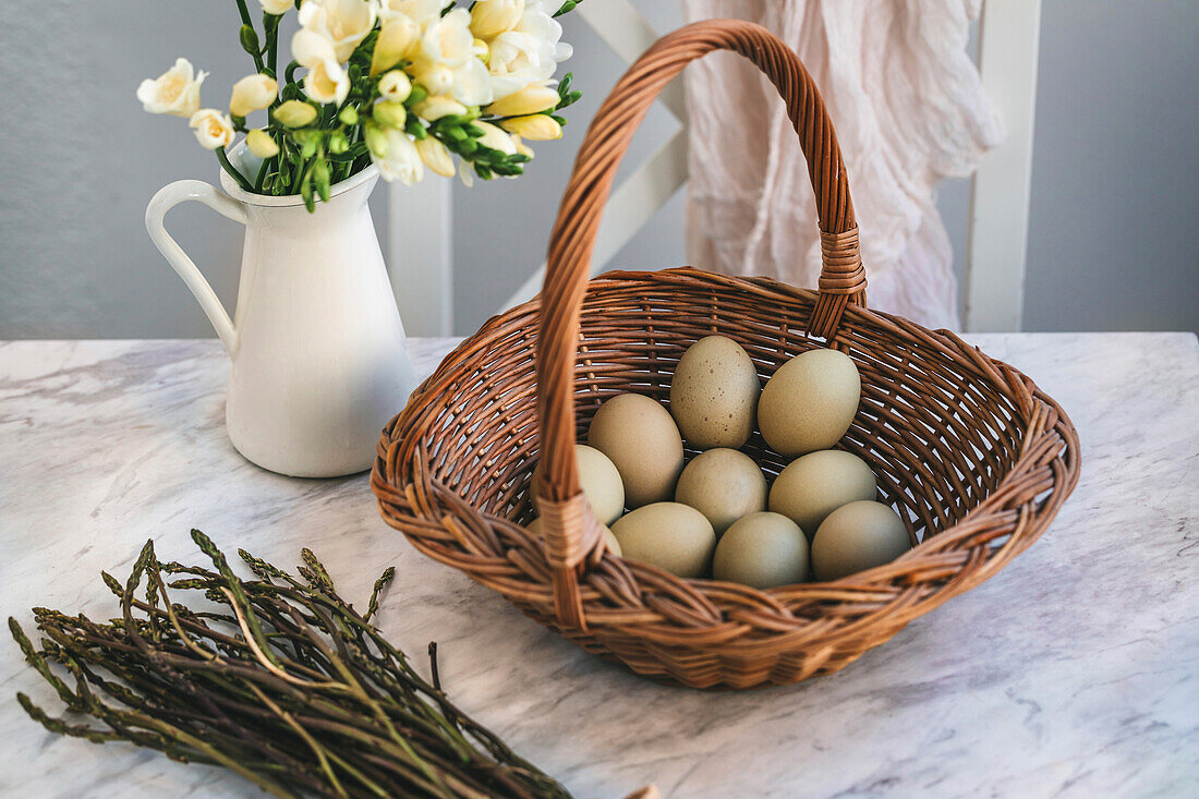 Green eggs in a wicker basket on a white marble table