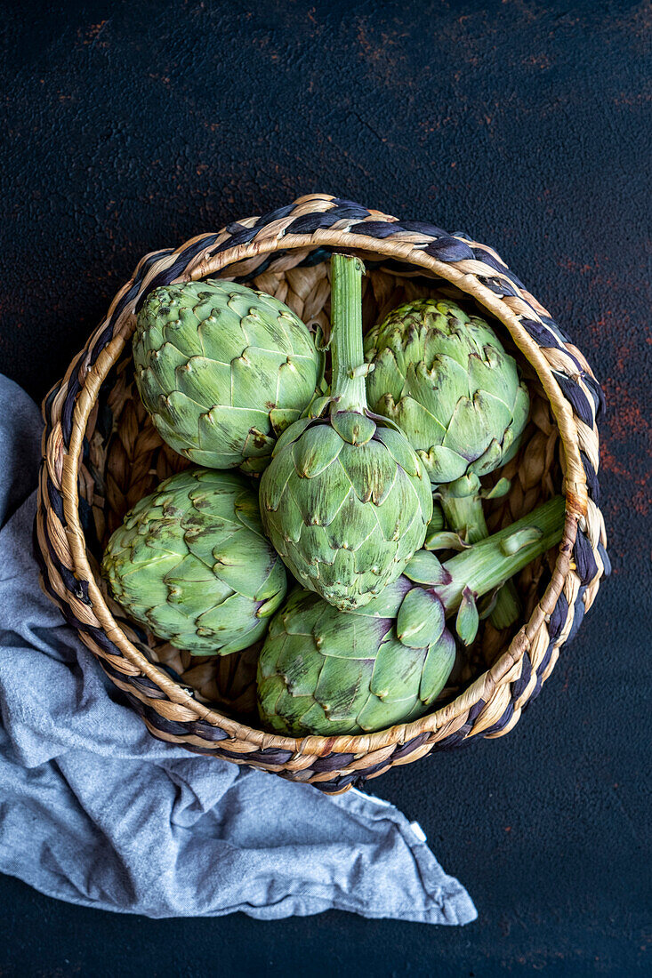 Fresh artichokes in a basket photographed against a dark background