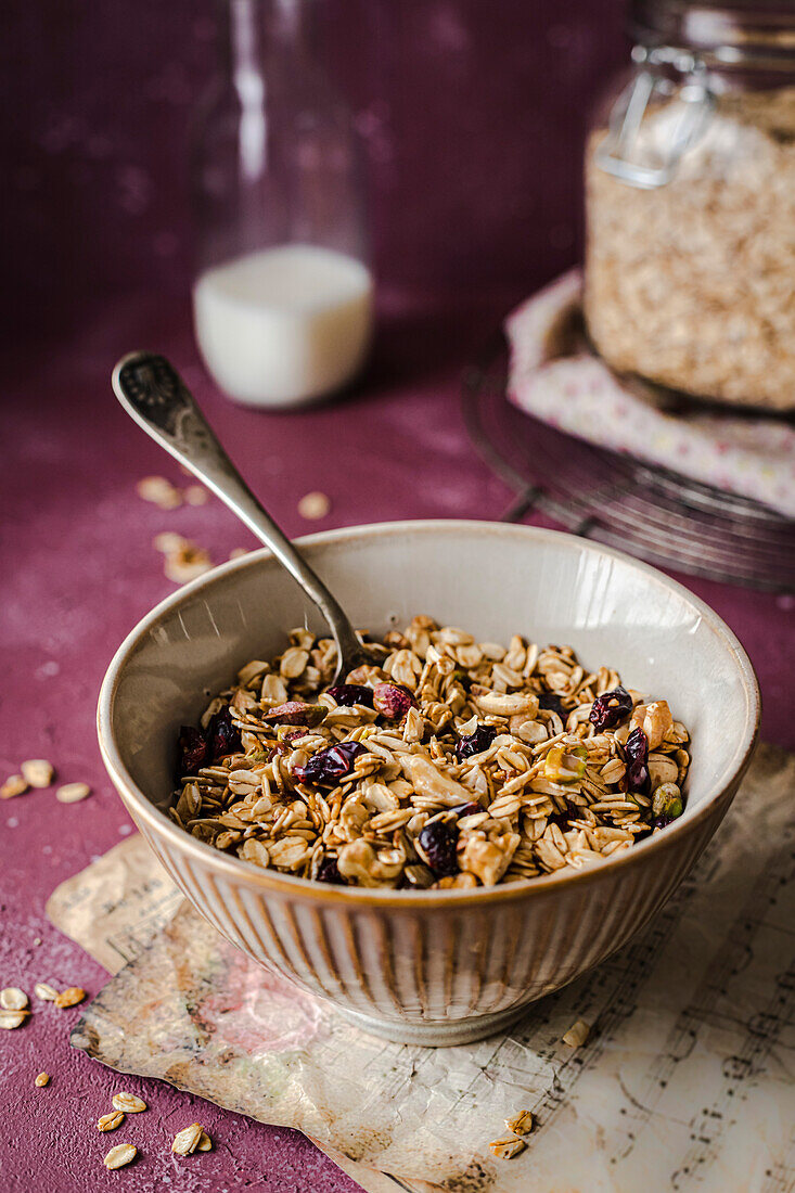 Bowl of muesli with an old spoon on a purple background, served with milk