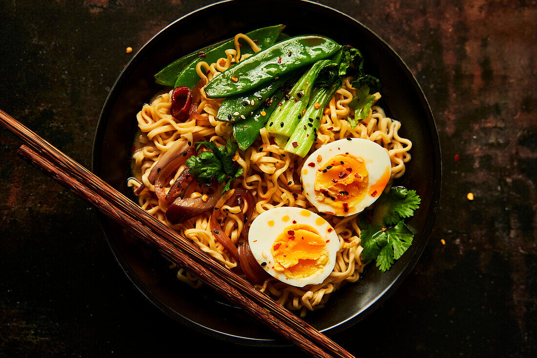 Egg and vegetable noodles in a bowl with chopsticks