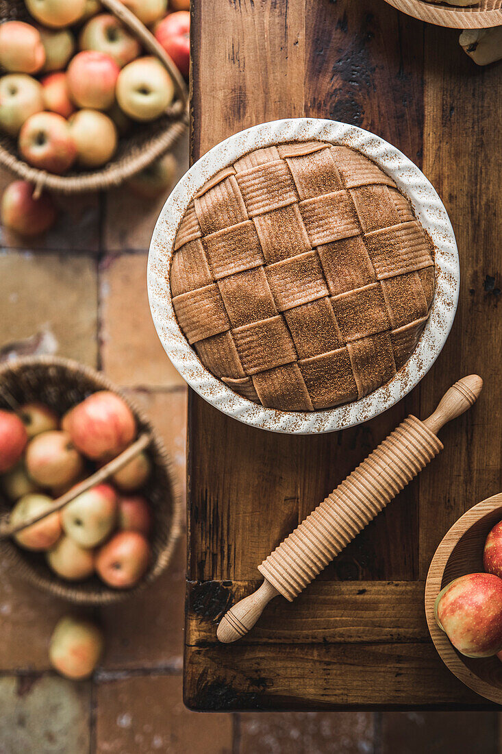 Apple pie with lattice pastry topping on a wooden kitchen table