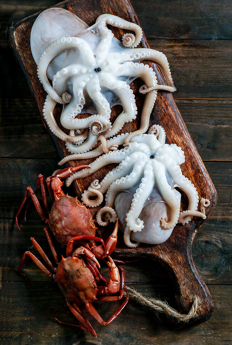 Seafood board with crabs, sardines and clams, fish and octopus on a dark wooden background. Top view, close up