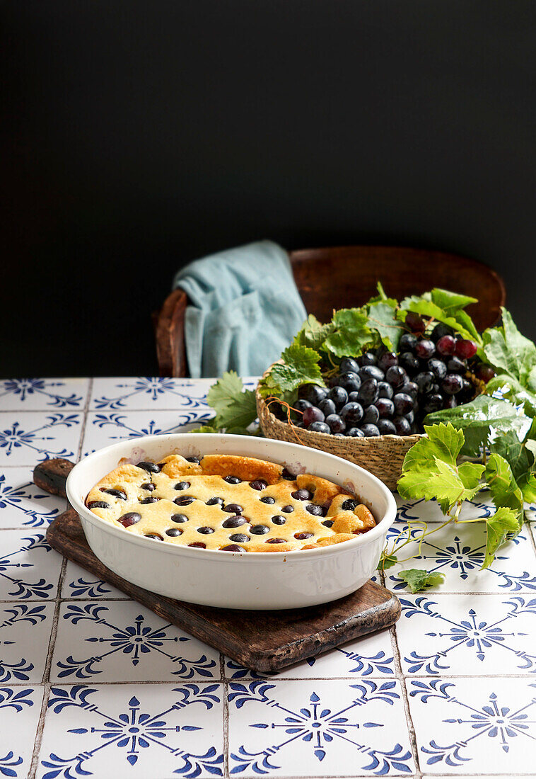 Rote Weintrauben-Clafoutis, französische Küche. auf einem Tisch aus Keramikfliesen mit blauem Muster