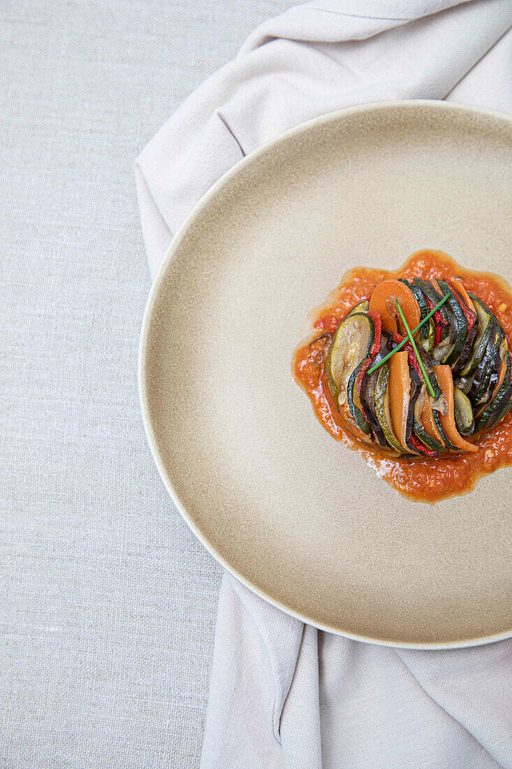 A modern take on Ratatouille, or mixed stewed vegateables, served on a ceramic plate