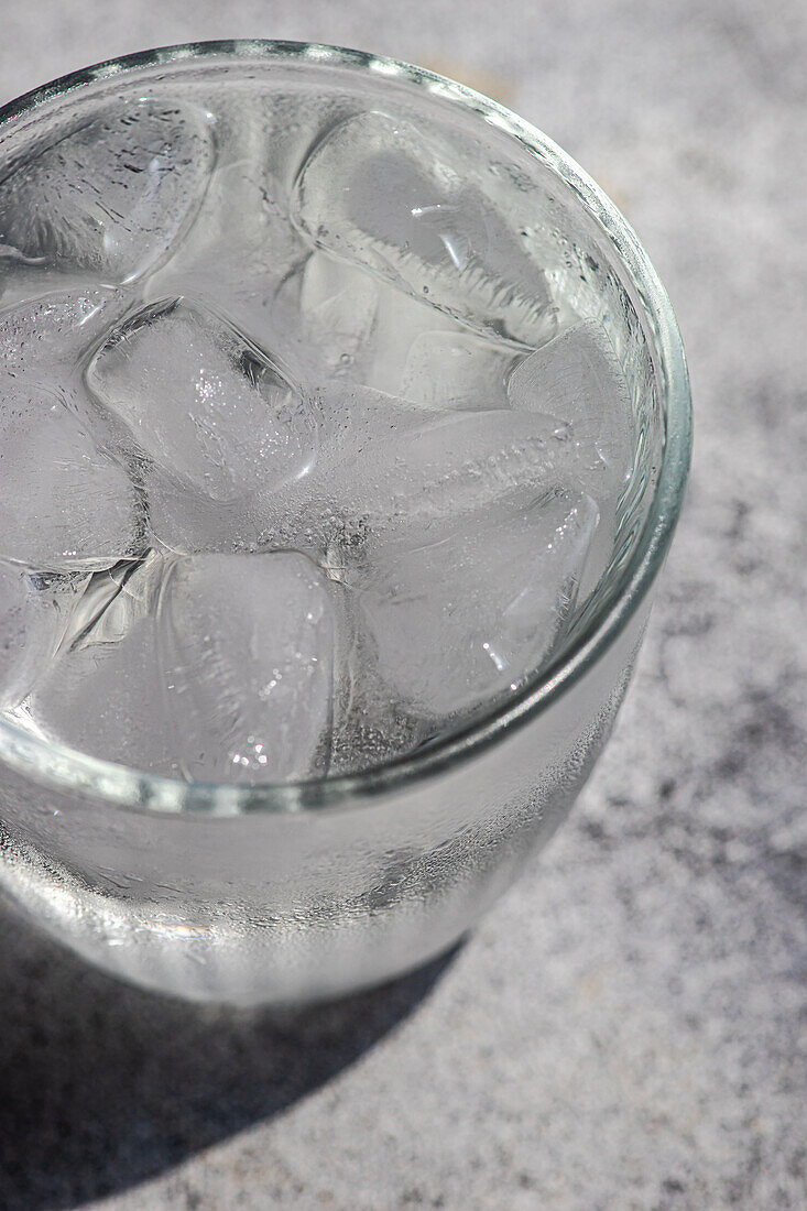 Von oben betrachtet ein Glas reines Wasser mit Eiswürfeln an einem heißen Sommertag