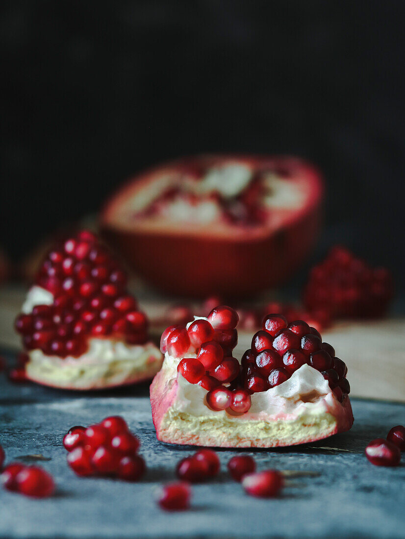 Open pomegranate on a cutting board over a gray dark gray background