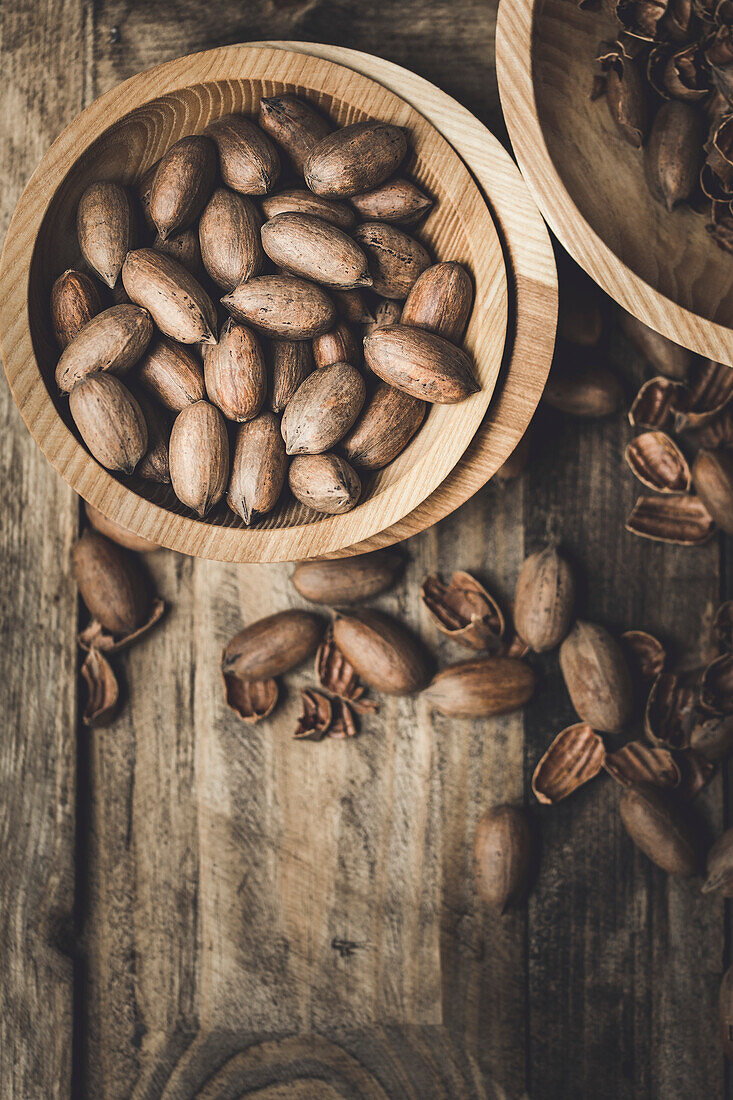 Fresh pecans and broken shells on a rustic wood background
