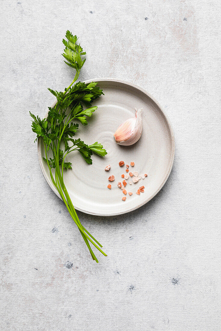 Petersilie, Knoblauch und rosa Salz auf einem Teller, bereit für die Zubereitung eines Gewürzes