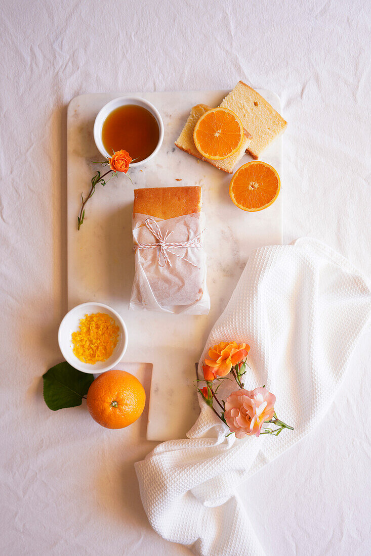Orangen-Madeira-Kuchen mit Sirup und Orangenschalen. Tischdekoration für den Nachmittagstee Flatlay