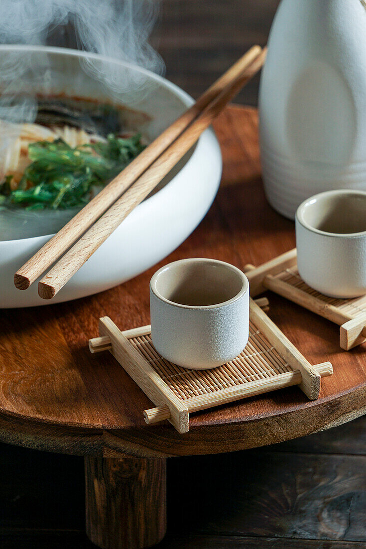 Japanese sake composition with Asian soup with rice noodles, Asian food ceremony with magnolia blossoms