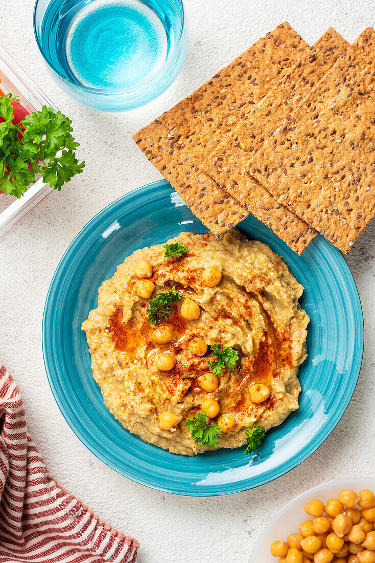 Chickpea hummus and galettes on a blue plate. View from above