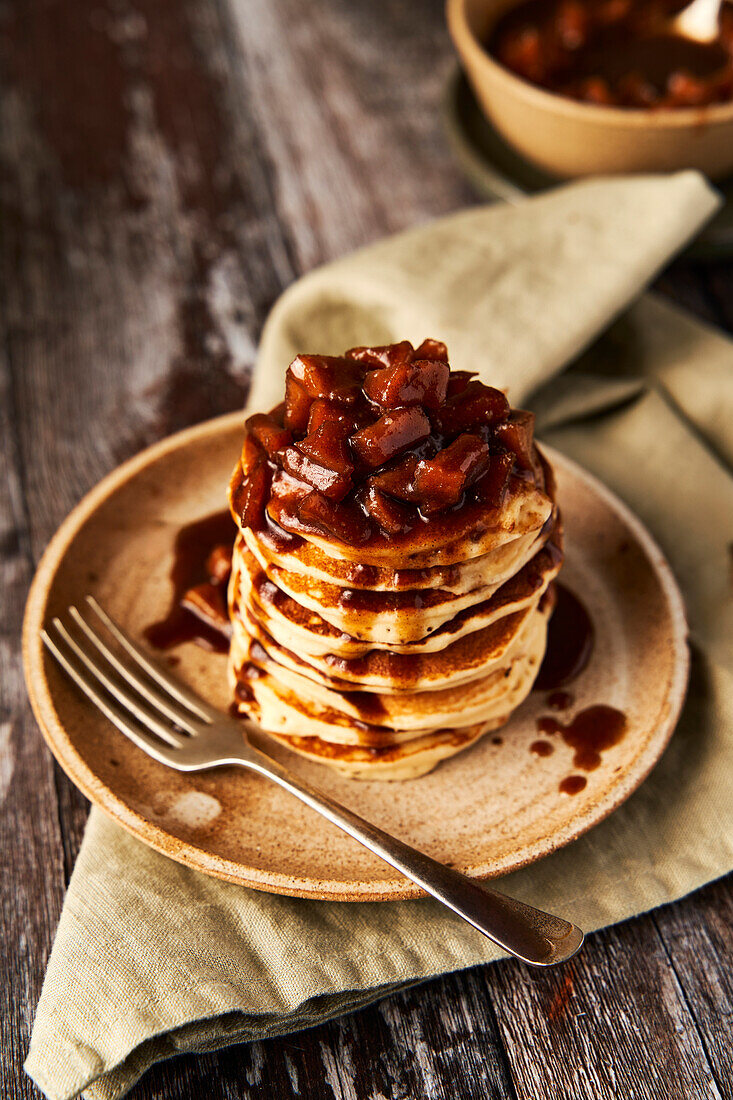 Apple and cinnamon pancake stack on wooden surface and sage green background