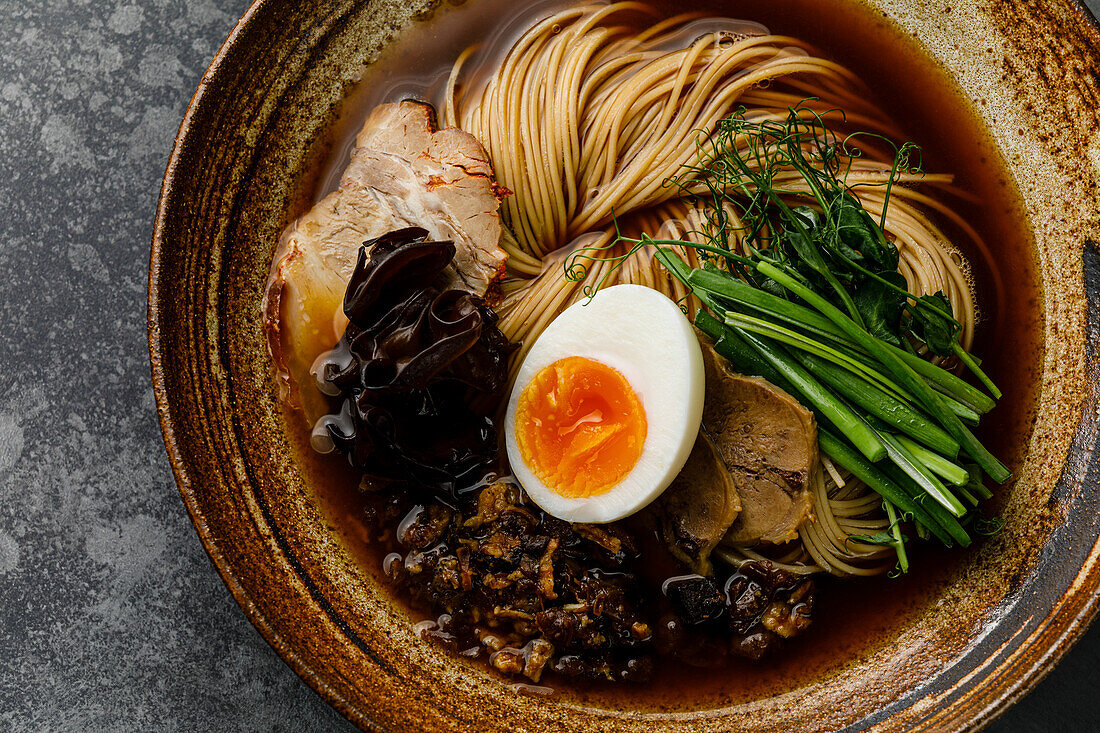 Ramen, Asian noodles in broth with beef tongue, mushrooms and eggs in a bowl