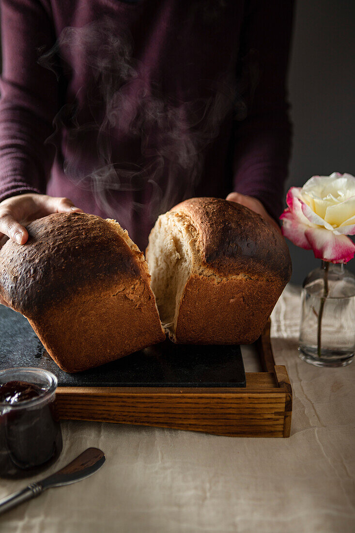 Homemade fresh milk bread with a woman breaking it