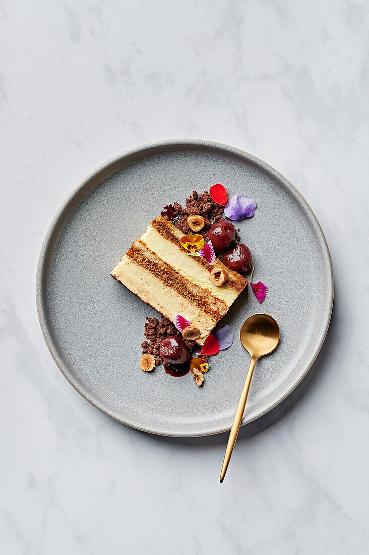 Slice of tiramisu with spiced cherry compote, salted chocolate crumb & candied hazelnuts