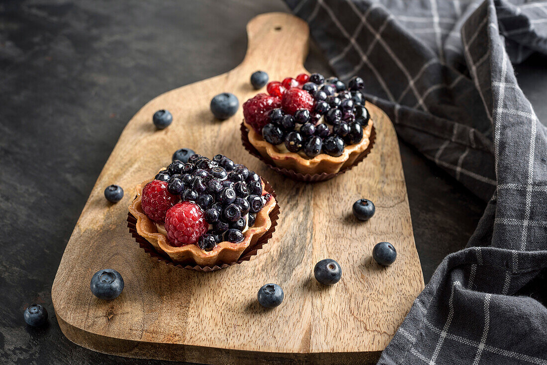 Cake basket with blueberries and raspberries. Pies on a chopping board