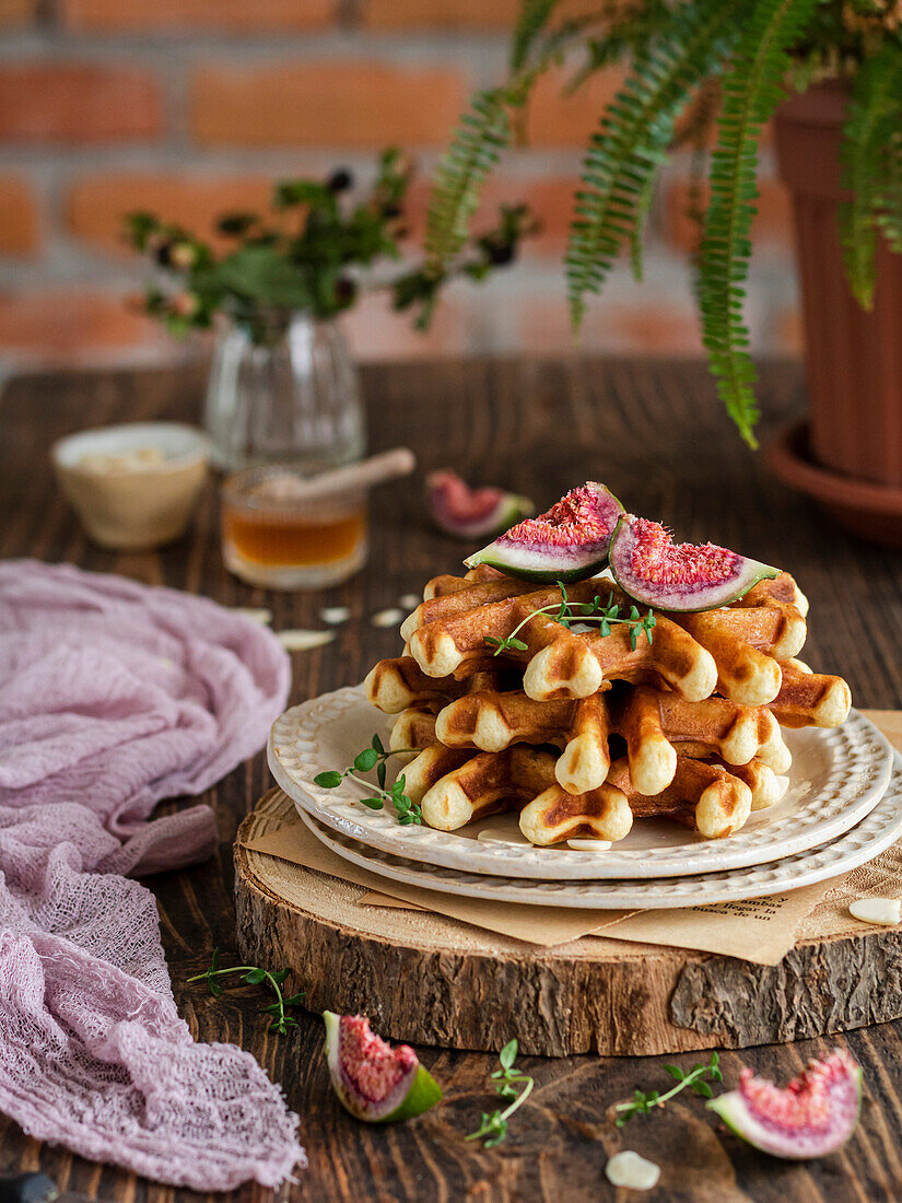 A stack of waffles with figs, thyme and honey on a rustic wooden board