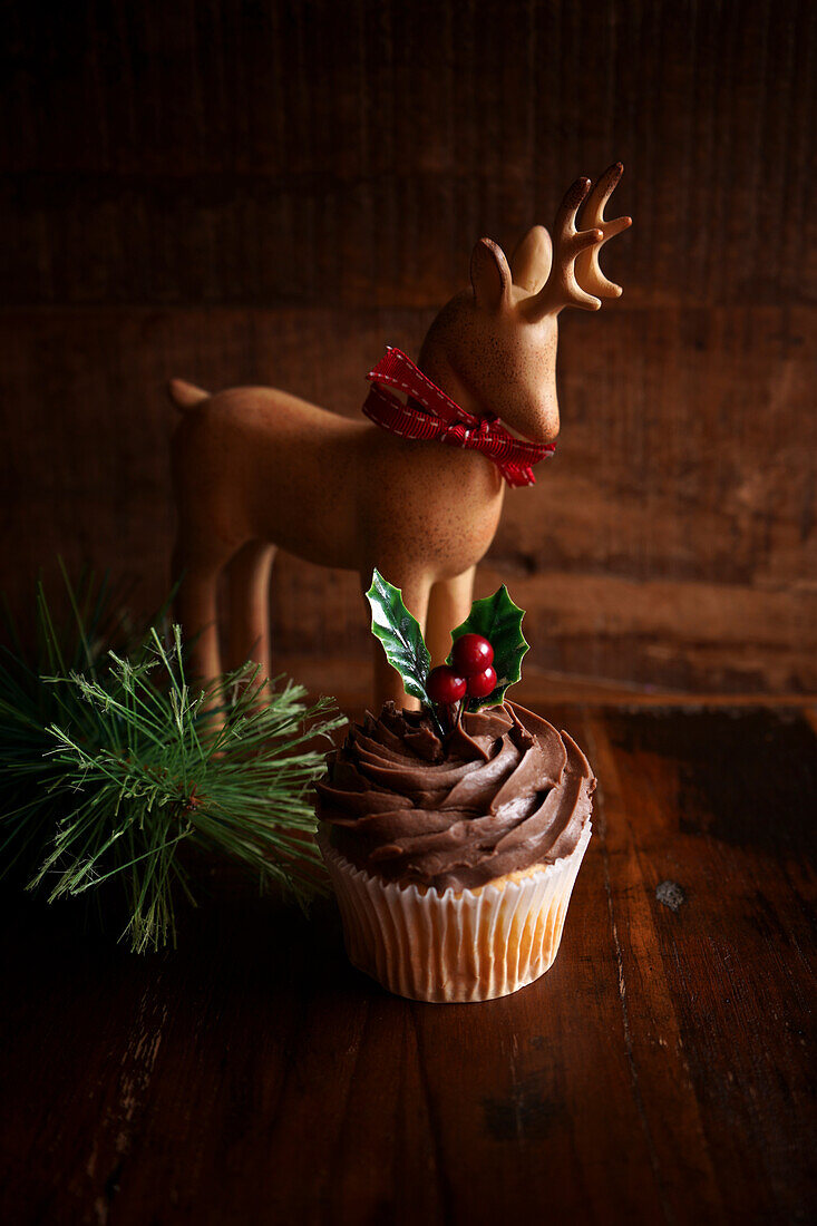 Weihnachtlicher Schokoladen-Cupcake vor einem dunklen Holzhintergrund