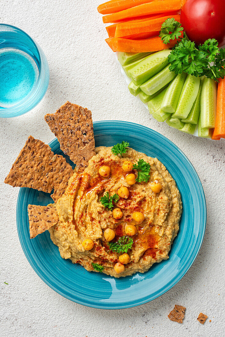 Chickpea hummus and galettes on a blue plate. View from above