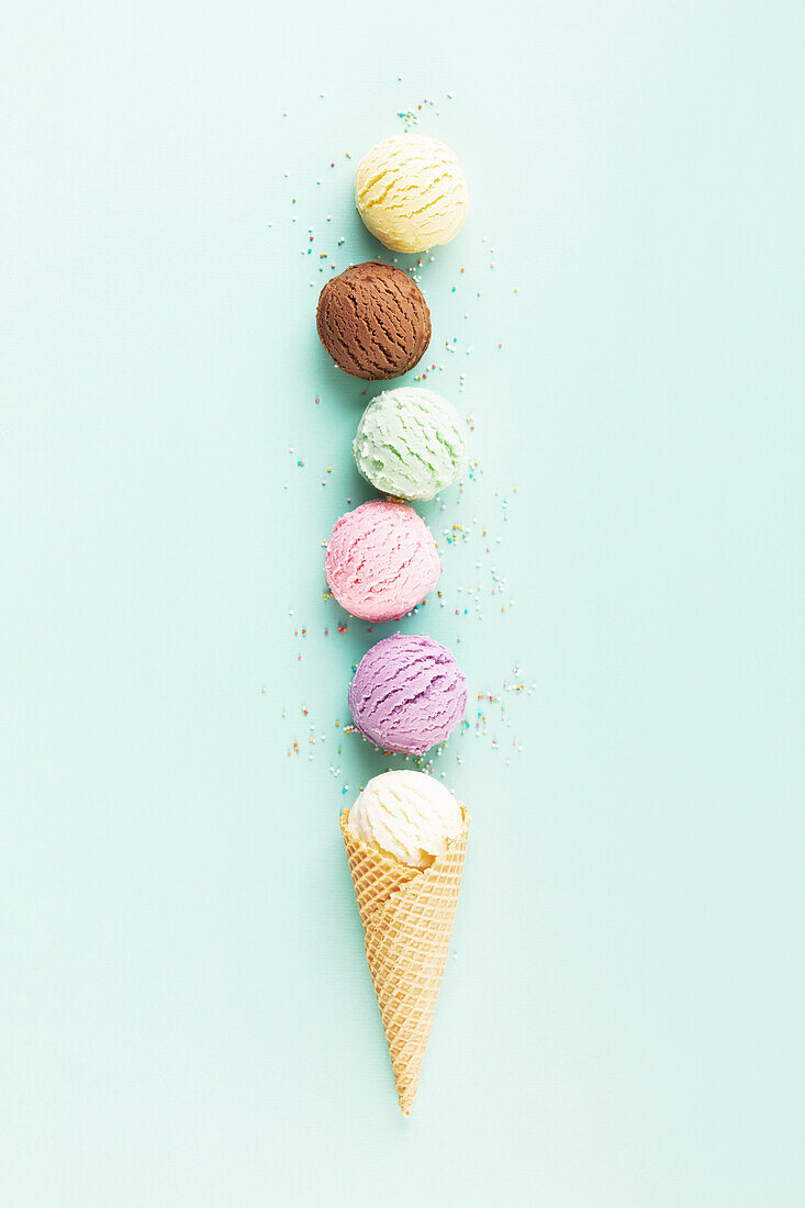 Flying ice cream scoops in a cone on a pastel-coloured light blue background. Summery minimal concept