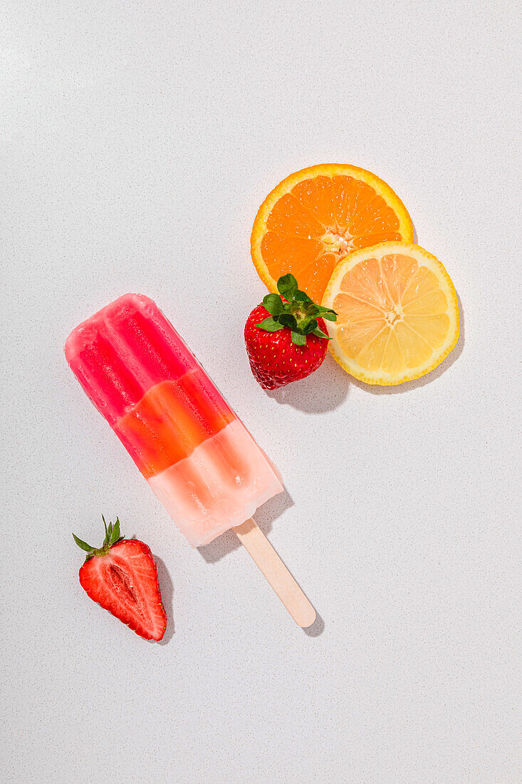 Fruit popsicle with 3 flavours on a white marble background