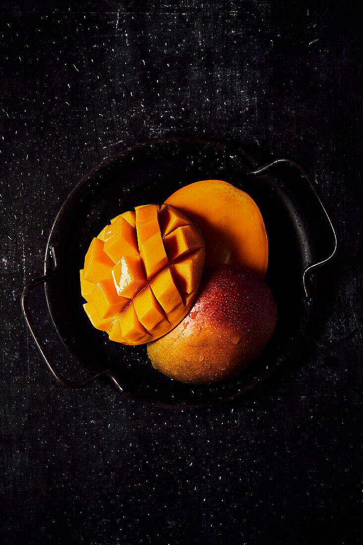 Frische Mango auf schwarzem Tablett und schwarzem Hintergrund
