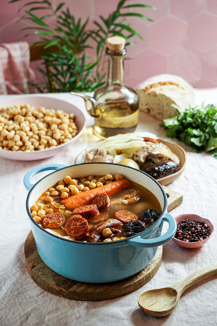 Cocido Madrileño, a traditional Spanish dish, a chickpea-based stew from Madrid with pink ceramic tiles in the background