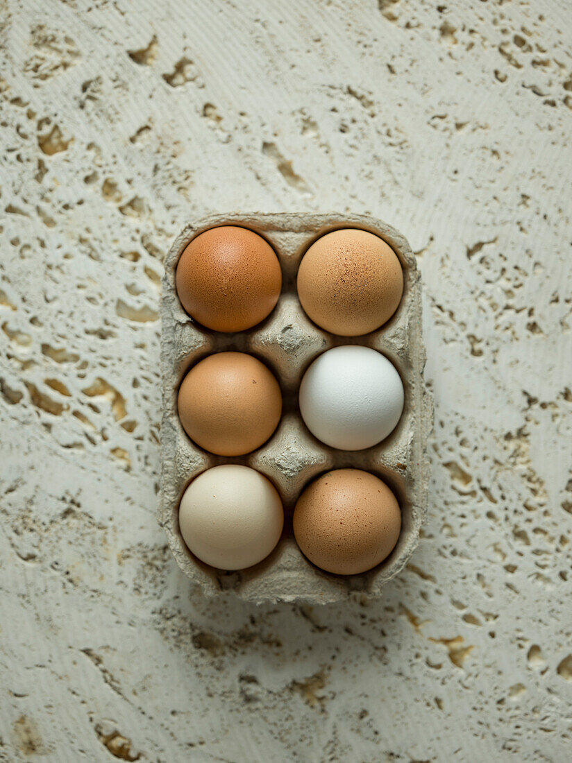 Eggs in cardboard carton on stone background