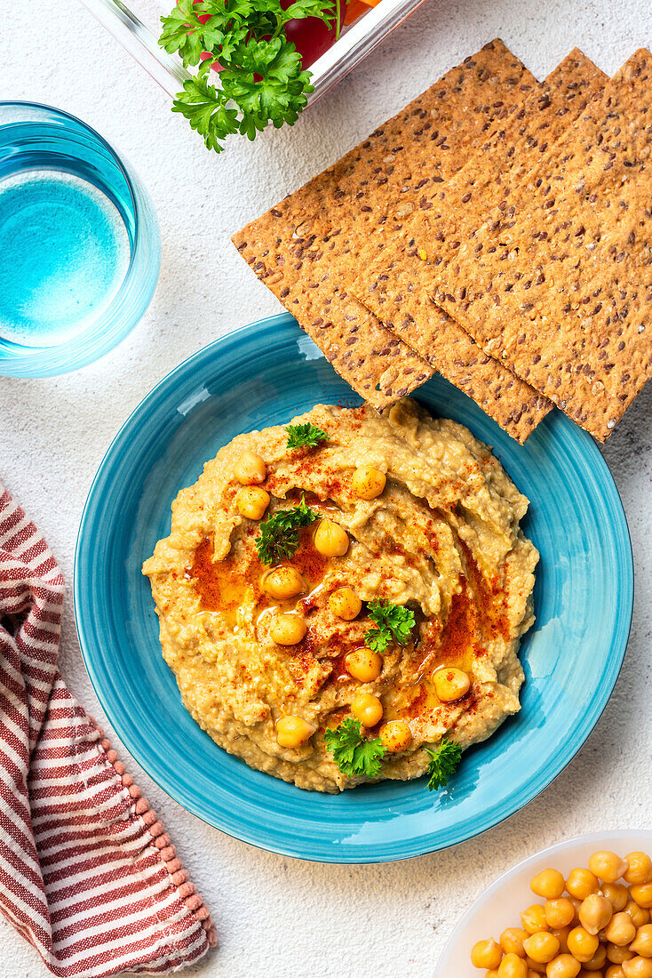 Kichererbsen-Hummus und Galettes auf einem blauen Teller. Ansicht von oben