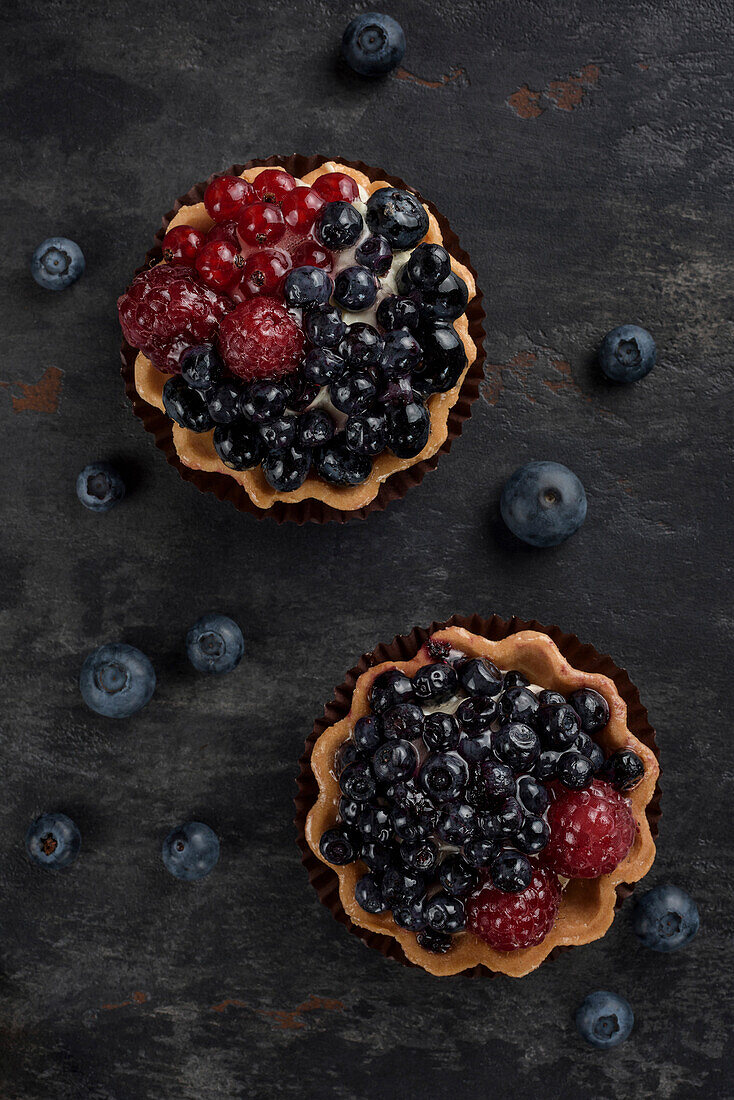 Gebäckkorb mit Heidelbeeren und Himbeeren. Torte auf dunklem Hintergrund. Ansicht von oben