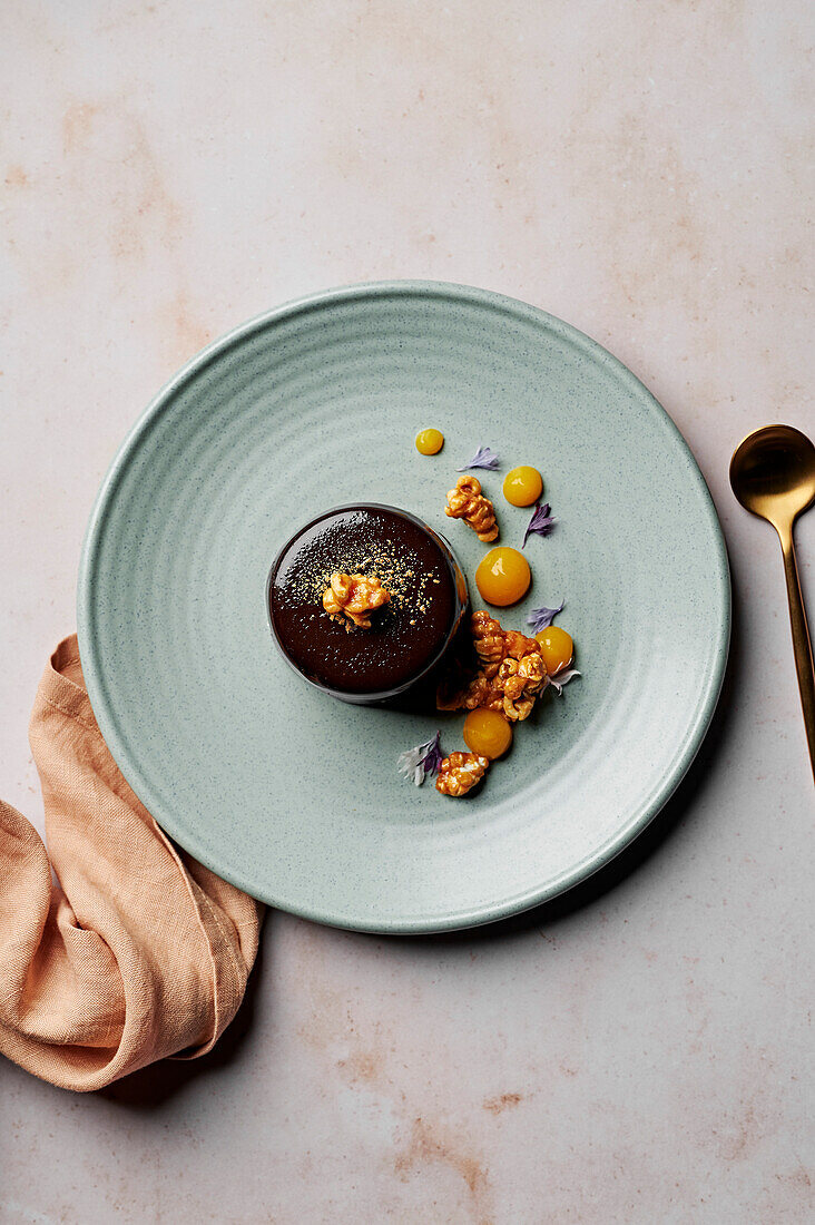 Flourless chocolate cake with mirror glaze, salted caramel popcorn and mandarin gel, from above