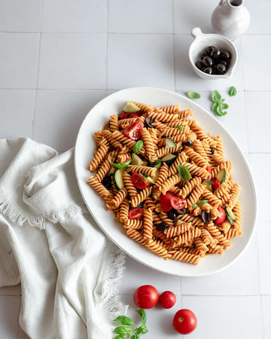 Mediterranean pasta bowl with fresh basil, olives, cherry tomatoes and cucumber