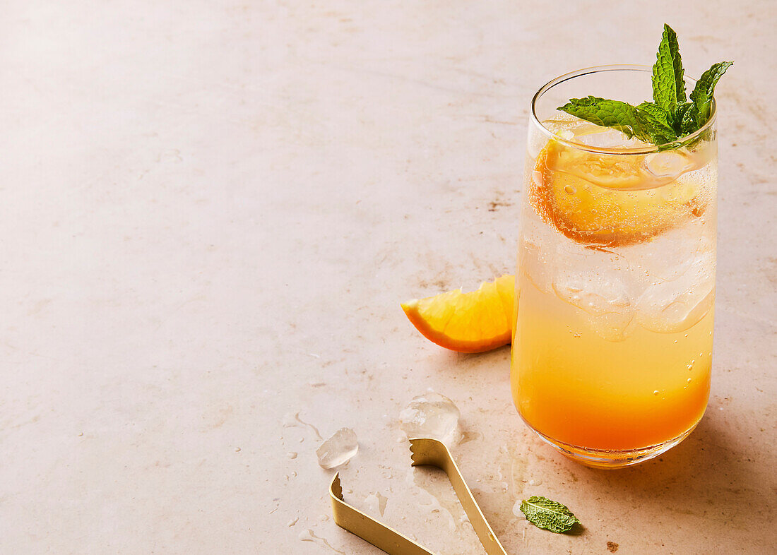 Orange-coloured sparkling cocktail with mint garnish