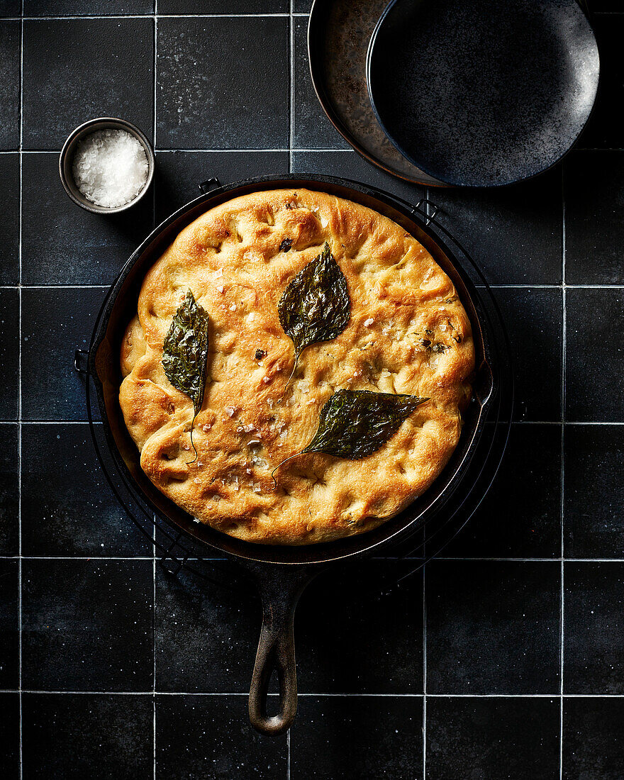 Gebackene Focaccia mit Perillablättern auf schwarzer Fliese