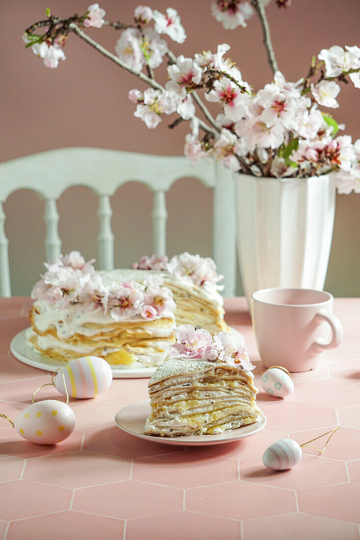 Crepe cake or blini cake for Easter celebrations, pink background, almond blossoms