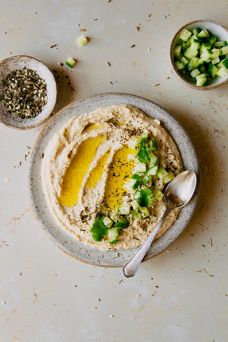Creamy hummus dip with cucumber and olive oil flatlay