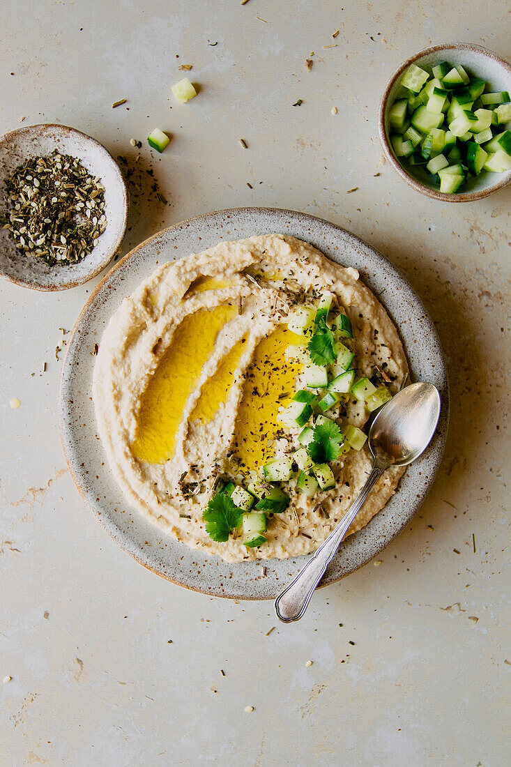 Cremiger Hummus-Dip mit Gurke und Olivenöl-Flatlay