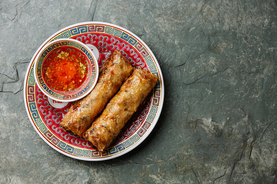 Spring rolls with sauce on stone background copy space