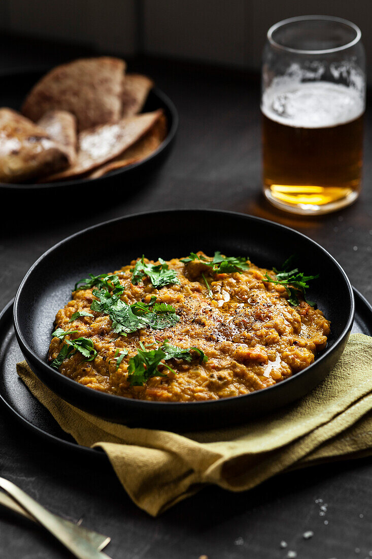 Side View of Indian Tarka Dal Curry with Roti, Beer and Cilantro