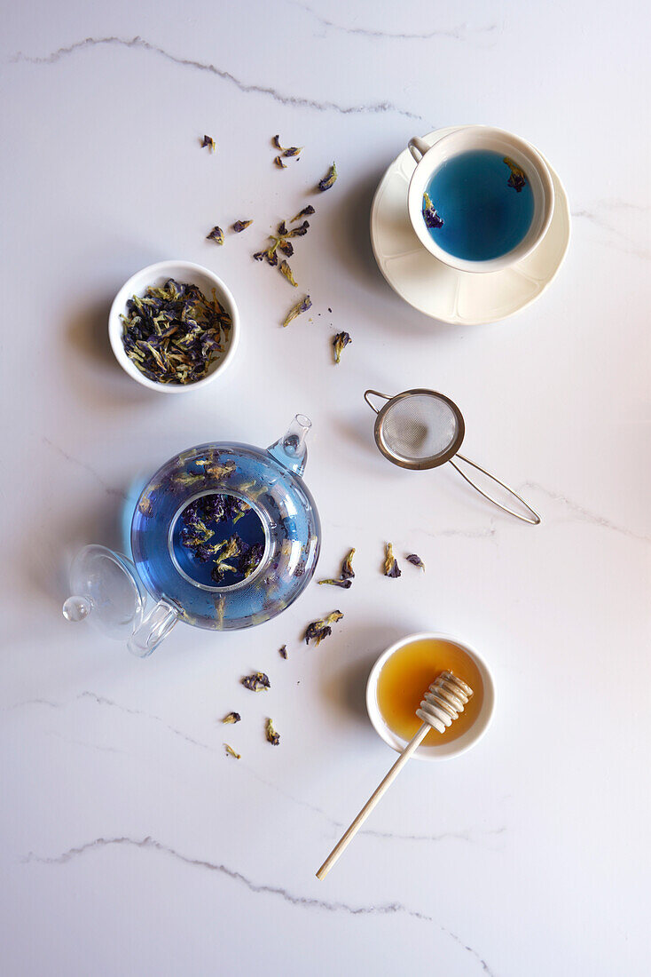 Blauer Schmetterlings-Erbsenblüten-Tee auf weißem Marmor-Hintergrund, Draufsicht, Flatlay