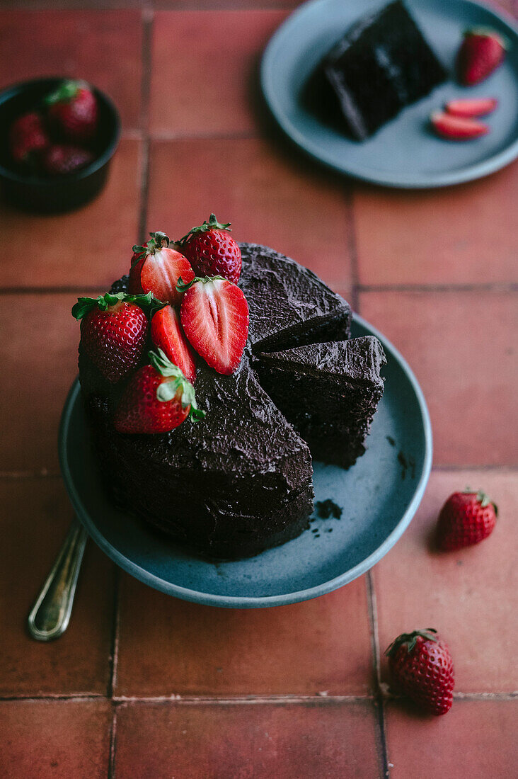 Schokoladenkuchen mit frischen Erdbeeren vor einem Terrakotta-Hintergrund