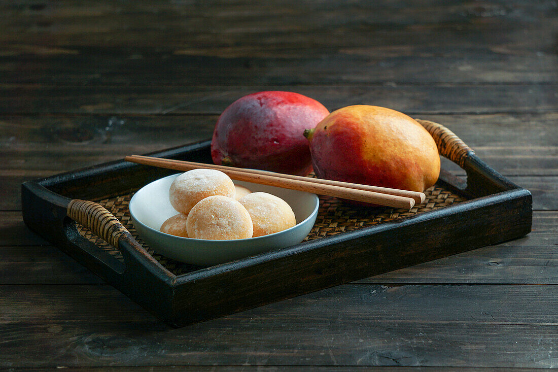 Japanische Mango-Mochi-Törtchen mit Eiscreme auf einem klassischen asiatischen Holztablett
