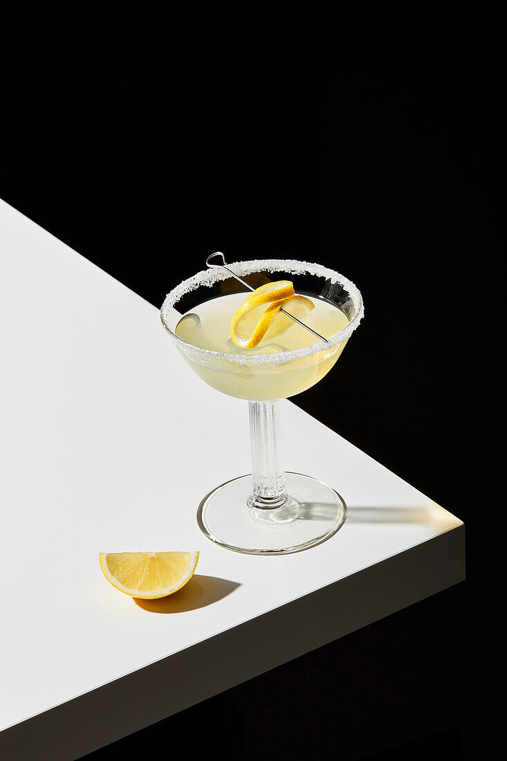 Lemon cocktail on a white table and black background