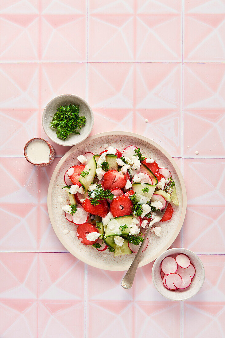 Spring Salad with Strawberries Cucumber Radish and Parsley on Pink Tile Background