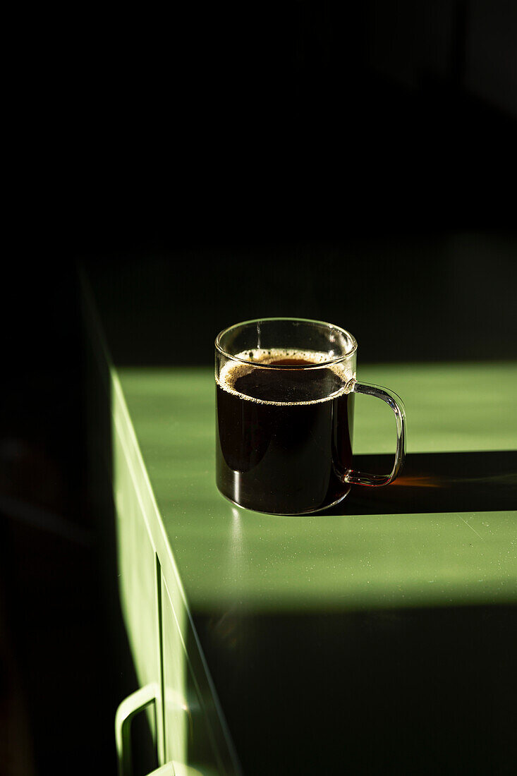 Coffee in glass mug on green table.