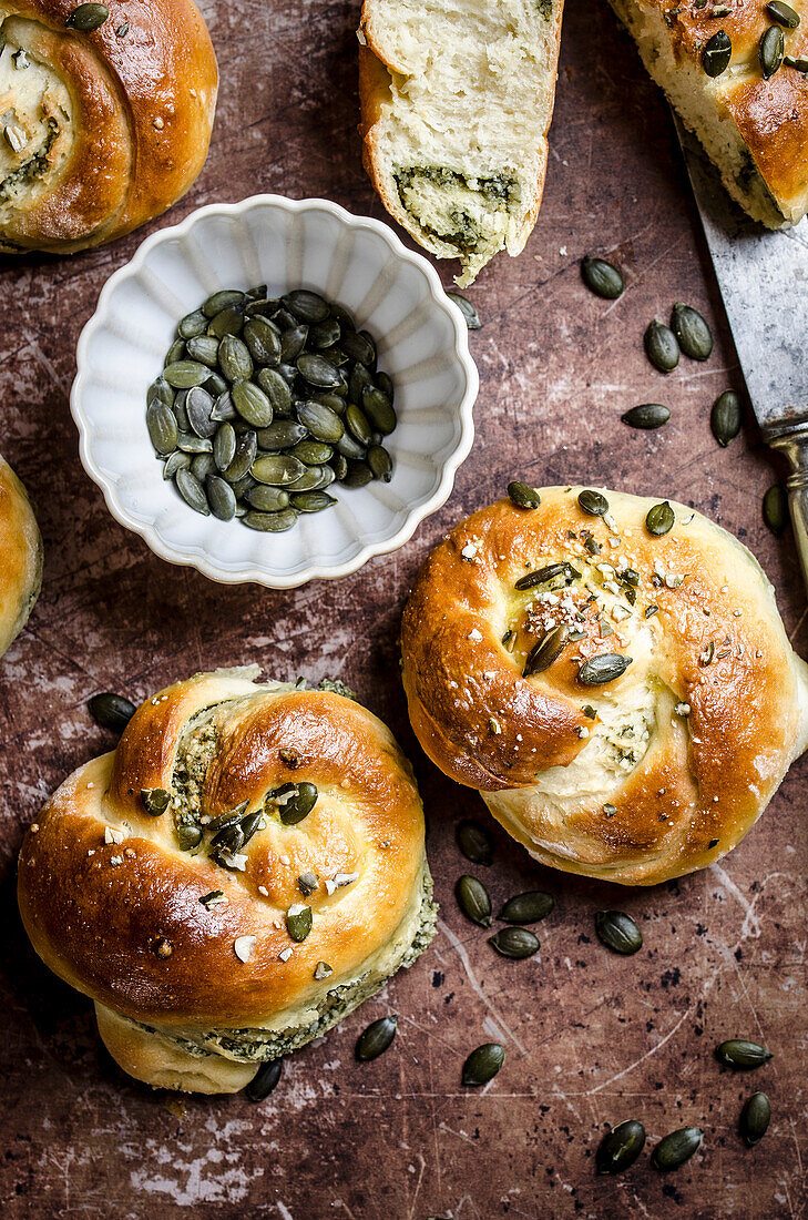 Bread roll with pumpkin seed cream, sprinkled with pumpkin seeds on a baking tray with emphasis