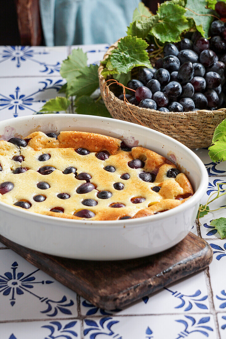 Rote Weintrauben-Clafoutis, französische Küche. auf einem Tisch aus Keramikfliesen mit blauem Muster