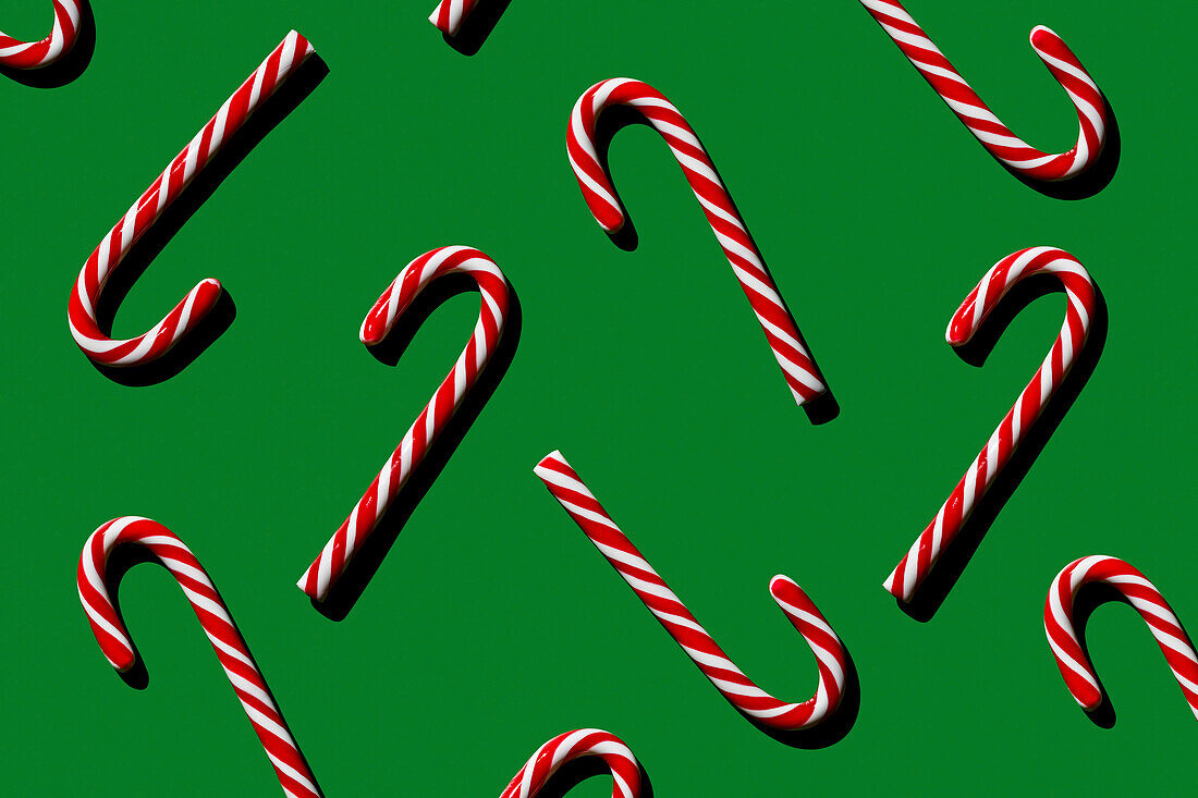 Pattern of Christmas candies cane stick on green background