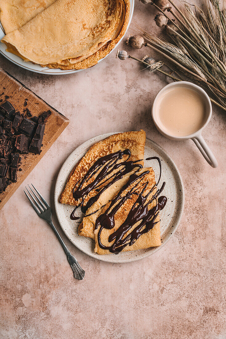 Crêpes mit geschmolzener Zartbitterschokolade beträufelt auf einem Keramikteller