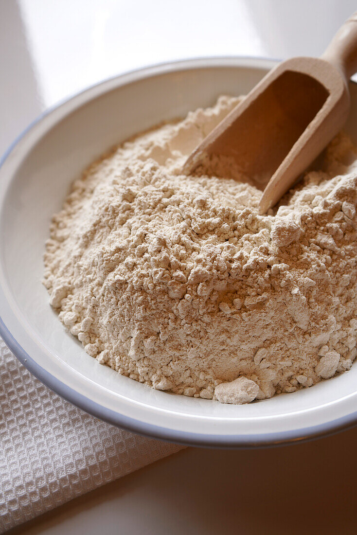 Buckwheat flour cooking and baking ingredient in white enamel bowl, closeup.